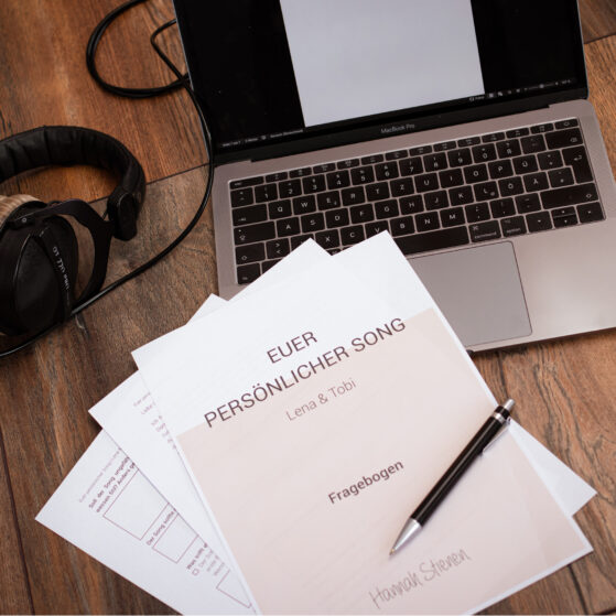 song-schreiben-lassen-euer-persoenlicher-song-hannah-stienen Flatlay von einem Laptop, Kopfhörer und einen Musterfragebogen, welchen die Kunden bekommen, wenn sie von Hannah Stienen einen persönlichen Song schreiben lassen.