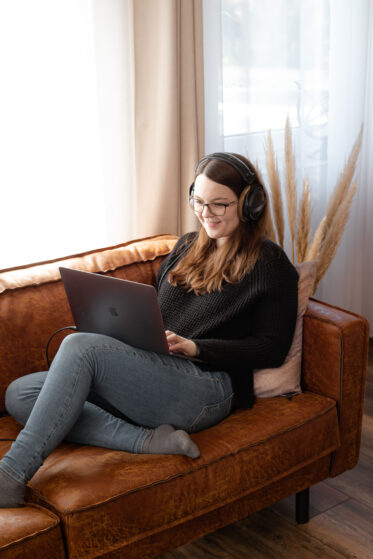 was-kostet-eine-hochzeitssaengerin-hannah-stienen-nrw-(c)studiolaecheln-3 Hochzeitssängerin Hannah Stienen sitzt mit ihrem Laptop auf der Couch und arbeitet an dem Blogpost, was eine Hochzeitssängerin kostet