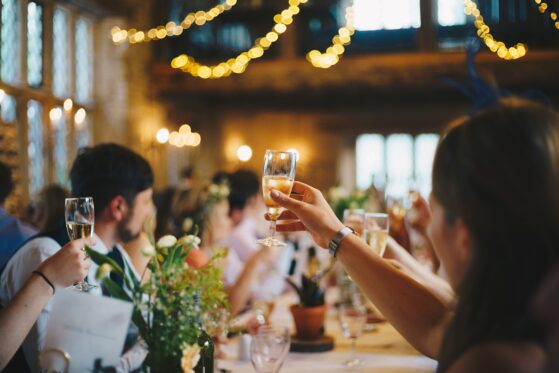 weihnachtsfeier-ideen-4 Weihnachtsfeier Ideen: Gäste sitzen am Tisch und heben ihr Glas