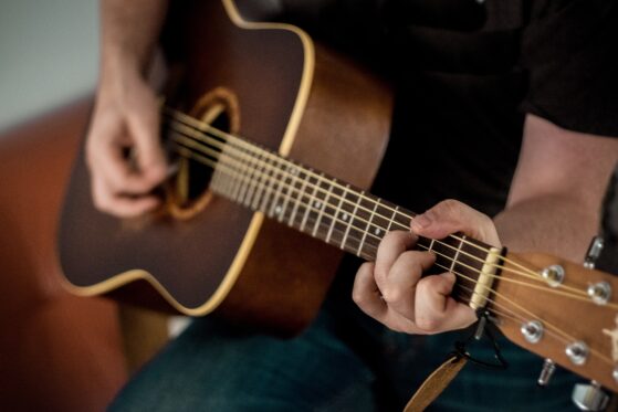 Nahaufnahme, wie ein Mann Akustikgitarre spielt