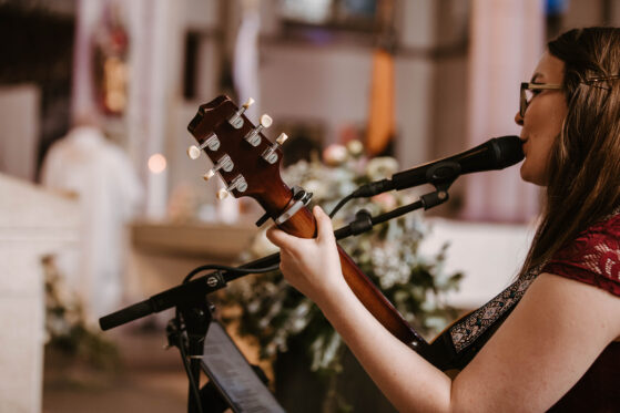 Hannah Stienen steht mit ihrer Gitarre in einer Kirche und singt.